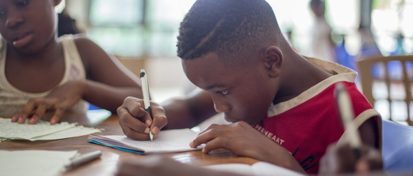 boy writing on printer paper near girl